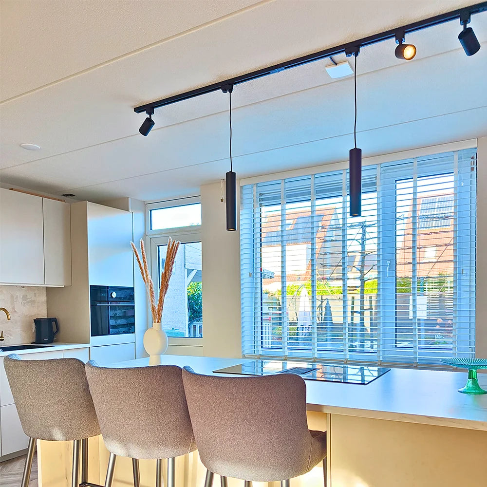 Zwarte rail hanglamp met lange buis en enkele fitting, hangend aan het railsysteem