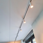 Witte rail met meerdere GU10 spots aan het plafond, spots branden