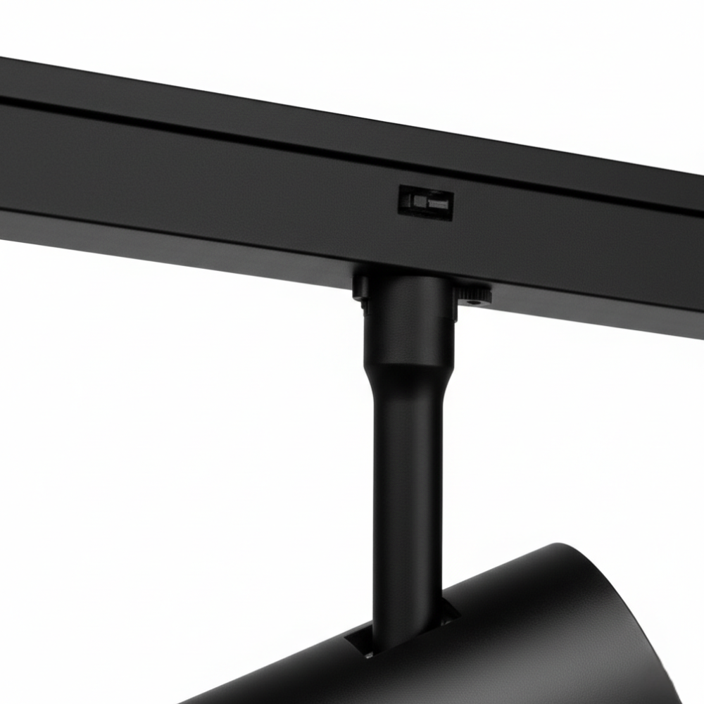 Zwarte railspot op rail, met kantelbare behuizing en lensopening.