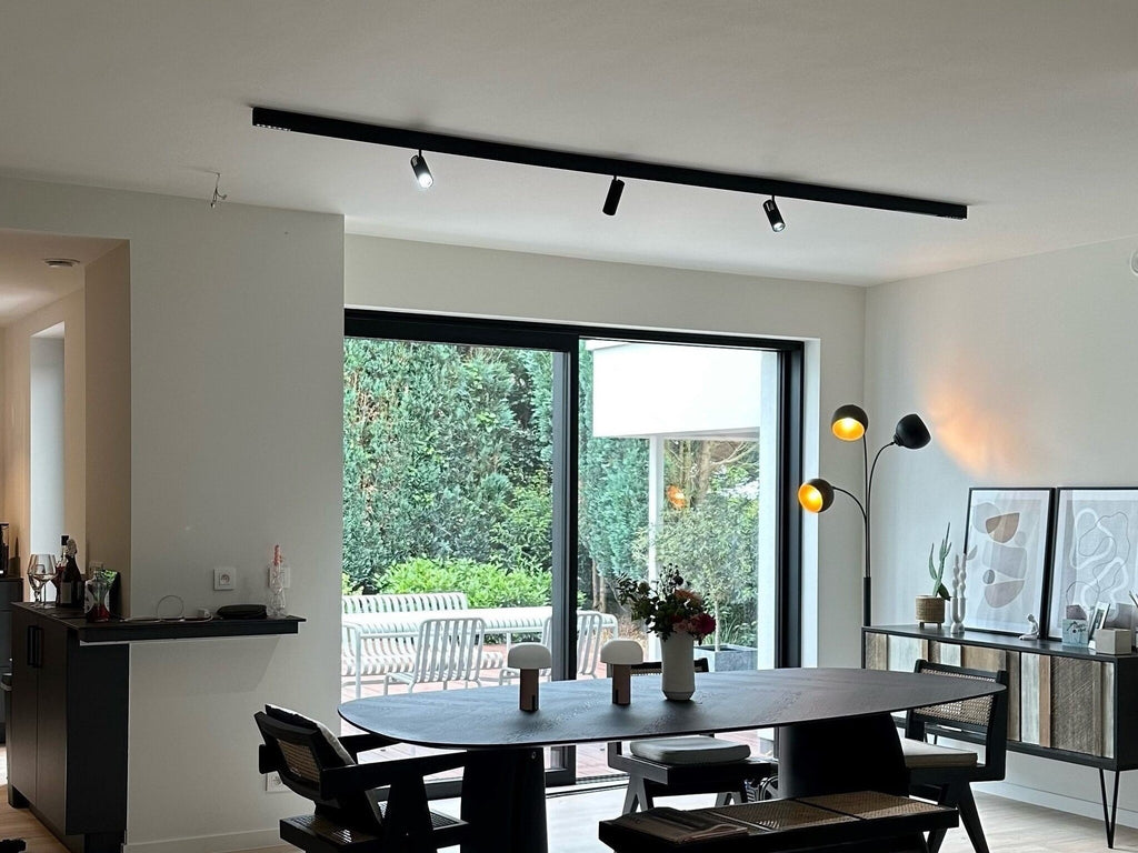 Zwarte plafondrail met meerdere railspots die warm licht geven.