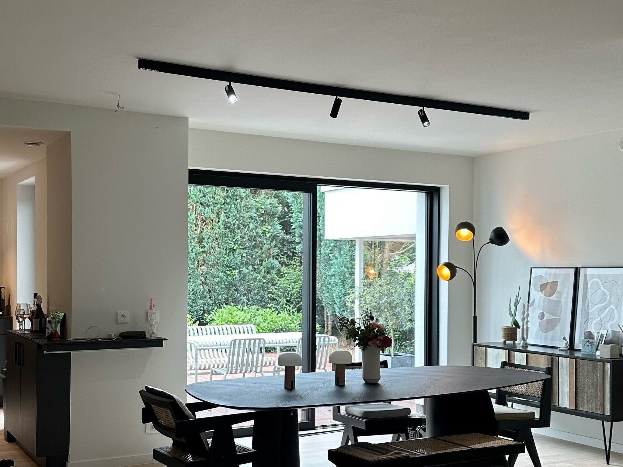 Zwarte plafondrail met meerdere railspots die warm licht geven.